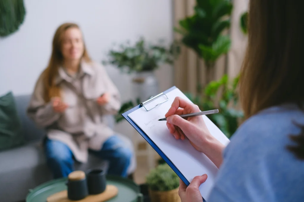 A therapist taking notes while speaking with a client